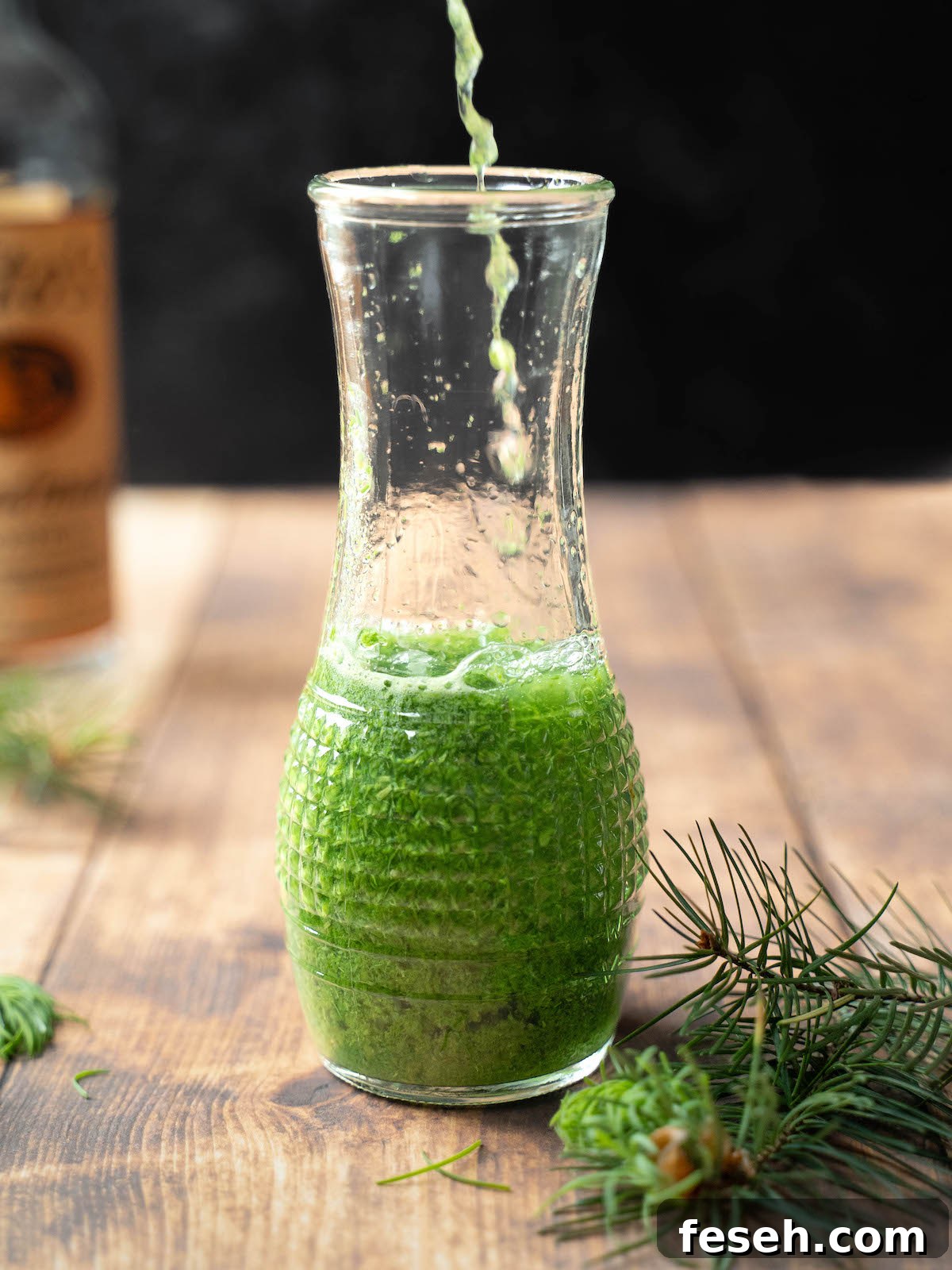 Fir tip-infused vodka pouring into a glass jar