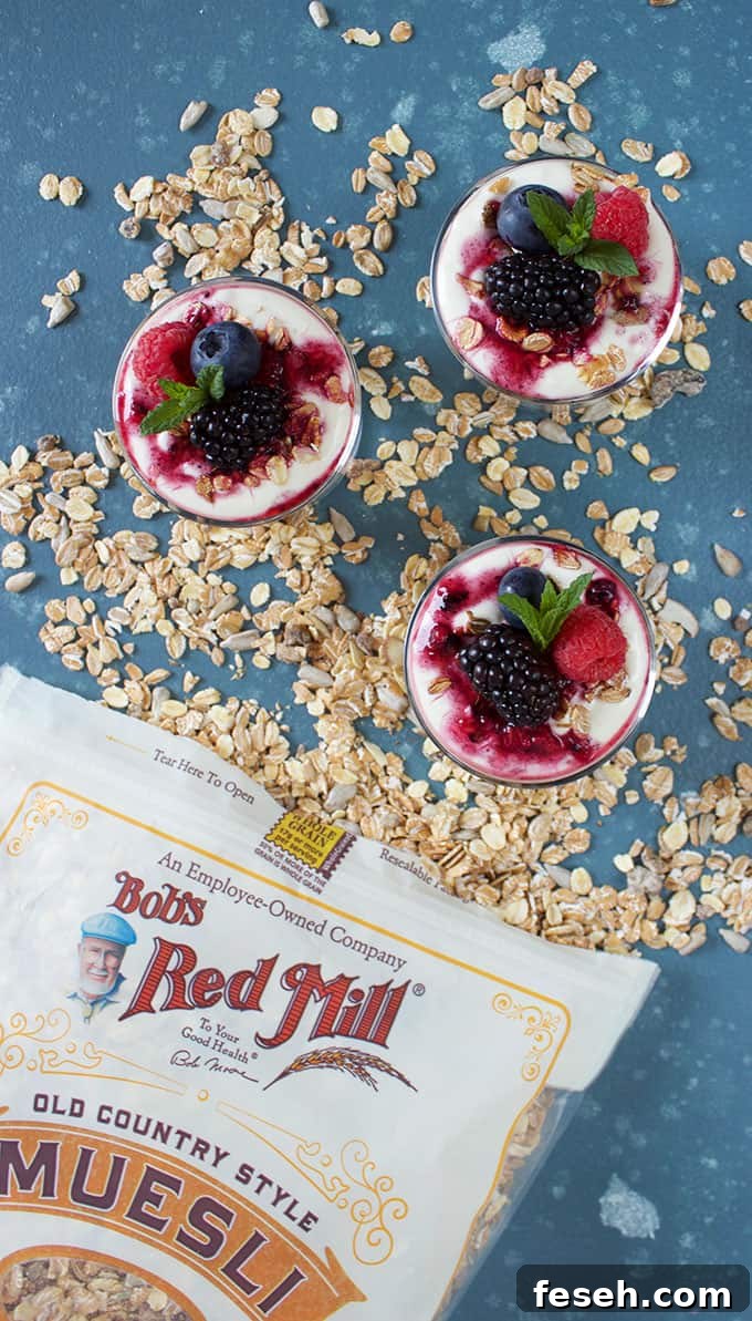 Three mini Breakfast Parfaits in a pile of muesli with a Bob's Red Mill Muesli bag on a blue background from TheSuburbanSoapbox.com