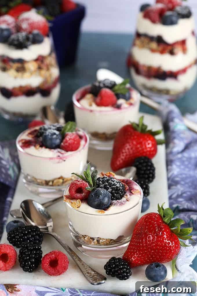 No Bake Cheesecake Breakfast Parfaits in a glass jar on a blue background with berries and a white spoon from TheSuburbanSoapbox.com