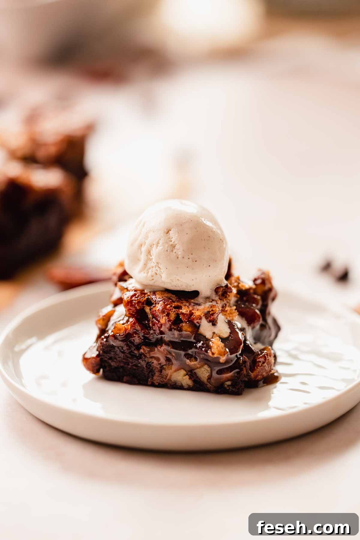 a pecan brownie square with a scoop of vanilla bean ice cream on top sitting on a plate