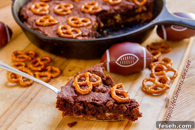 A brownie slice next to a cast iron skillet with more brownies.