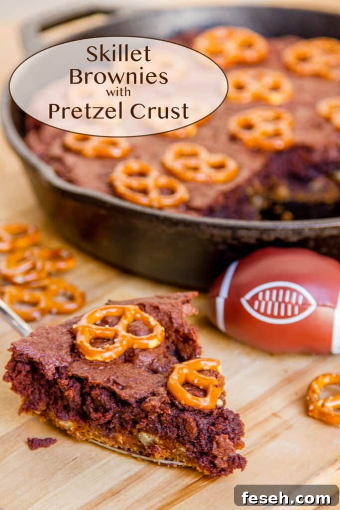 Skillet brownies with pretzel crust with a slice next to the cast iron skillet and a small football.