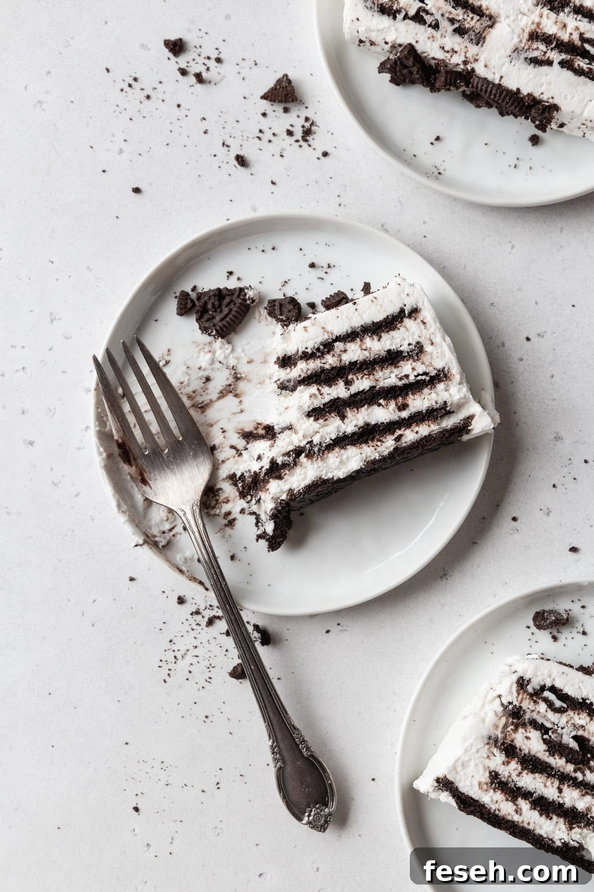 A partially eaten slice of icebox cake on a white plate with a fork.