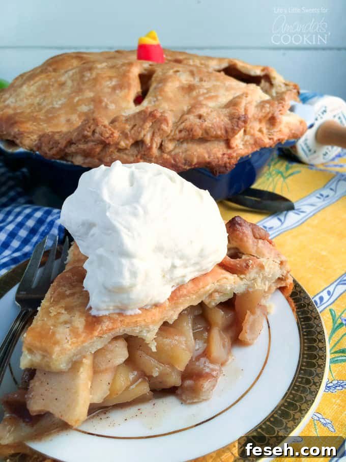 A slice of homemade apple pie on a plate with the whole pie in the background.