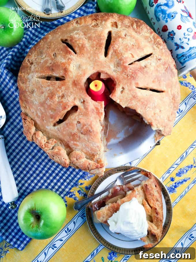 A whole homemade apple pie with a missing slice that is sitting on a plate to the side.