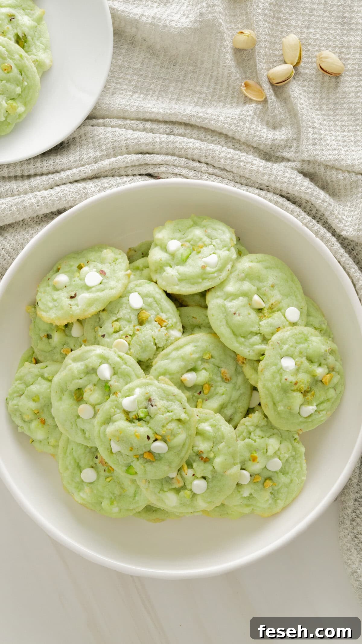 Top view of pistachio cookies in white serving platter with gray background.