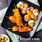 Spanish chicken kebabs on a black plate