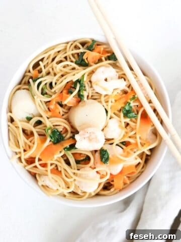 One Asian-inspired noodle bowl with a linen napkin to on the side and chopsticks on the top of the bowl.