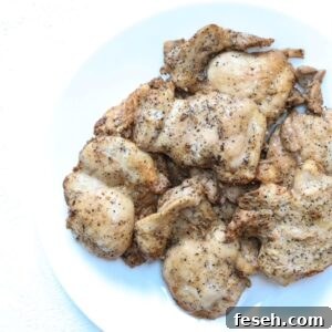 A pile of cooked marinated lemon pepper chicken on a white plate.