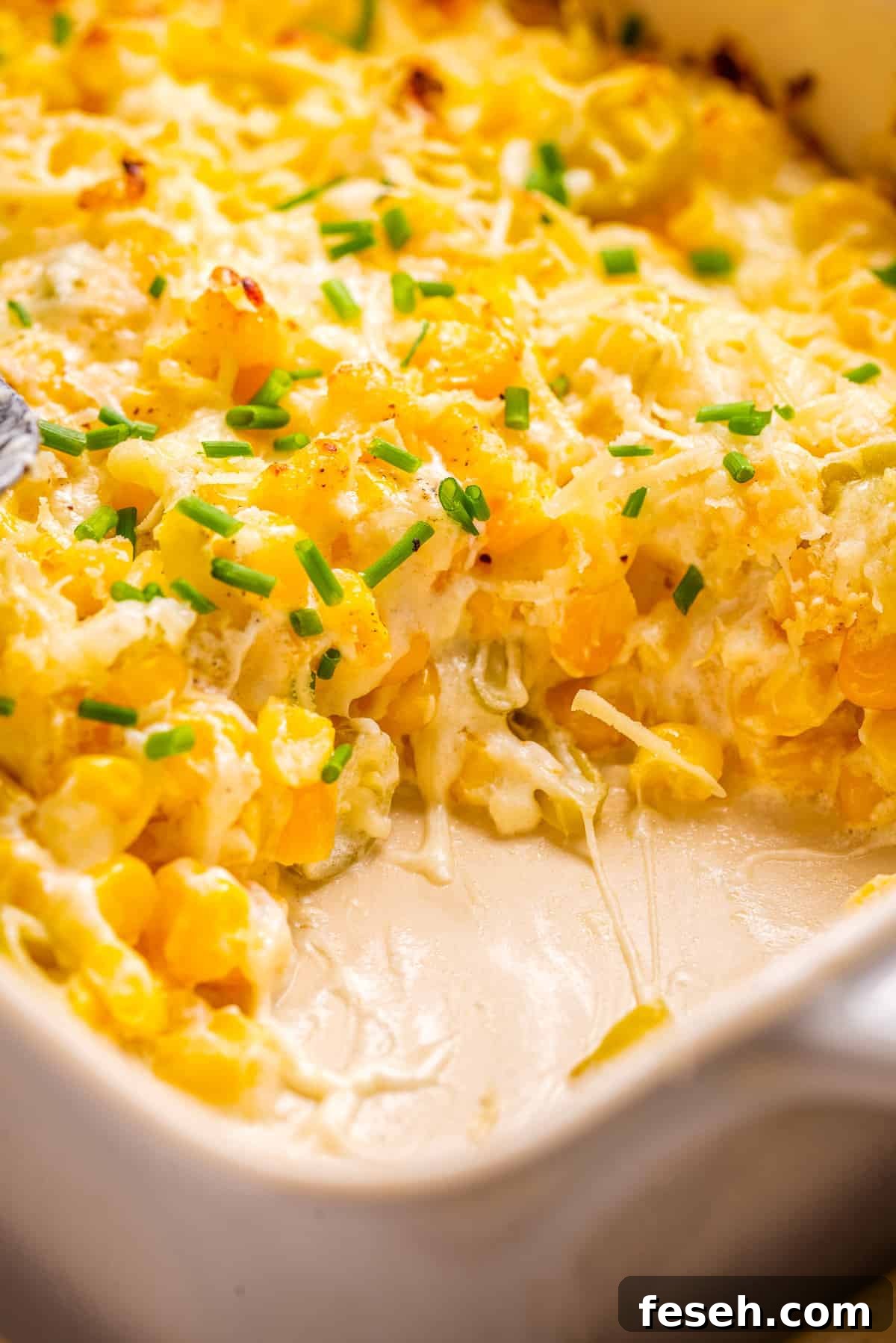 A close up image of corn casserole with cream cheese, with a portion taken out