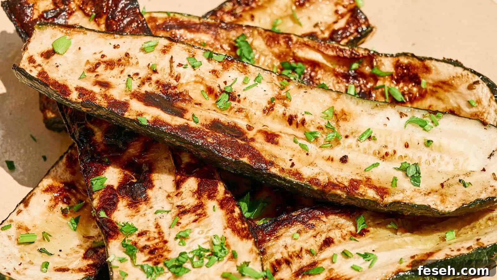 Grilled zucchini slices garnished with chopped herbs on a light-colored plate.