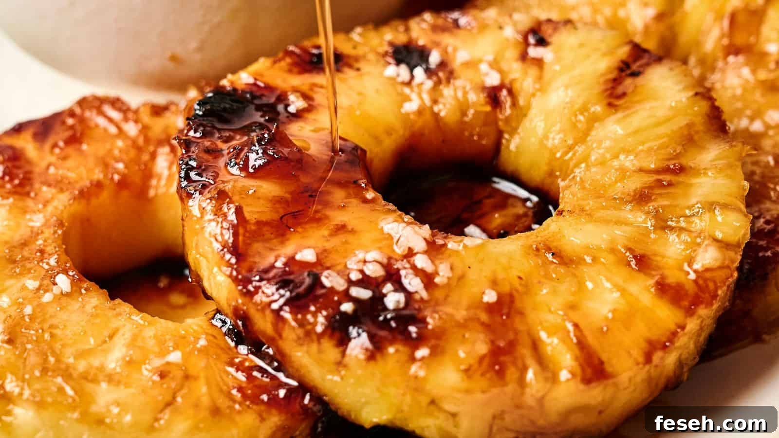 Close-up of grilled pineapple rings topped with coarse salt and drizzled with syrup.
