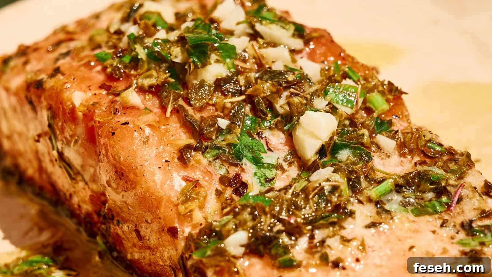 A close-up of a cooked salmon fillet topped with a mixture of chopped herbs, garlic, and seasonings.