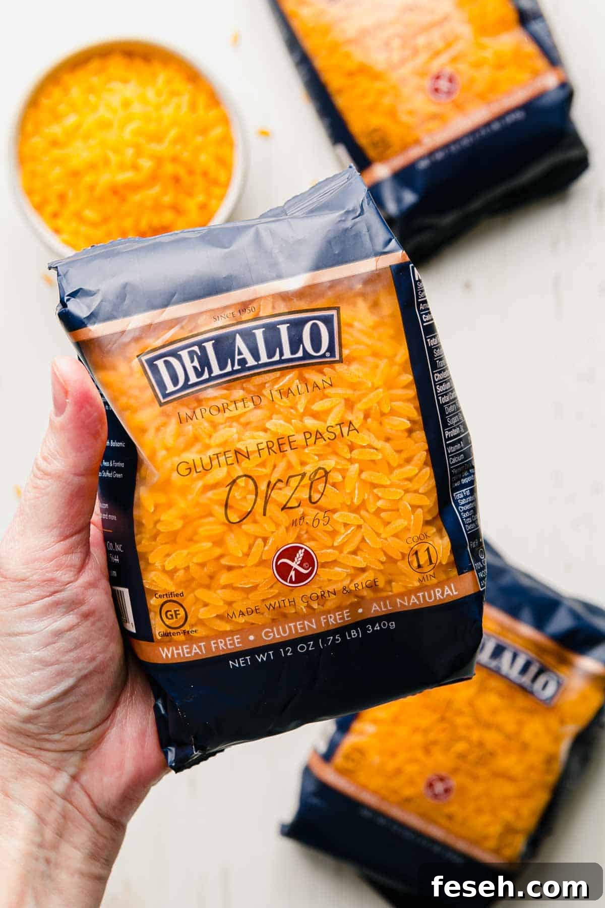 A package of dellalo gluten free orzo held by a hand.