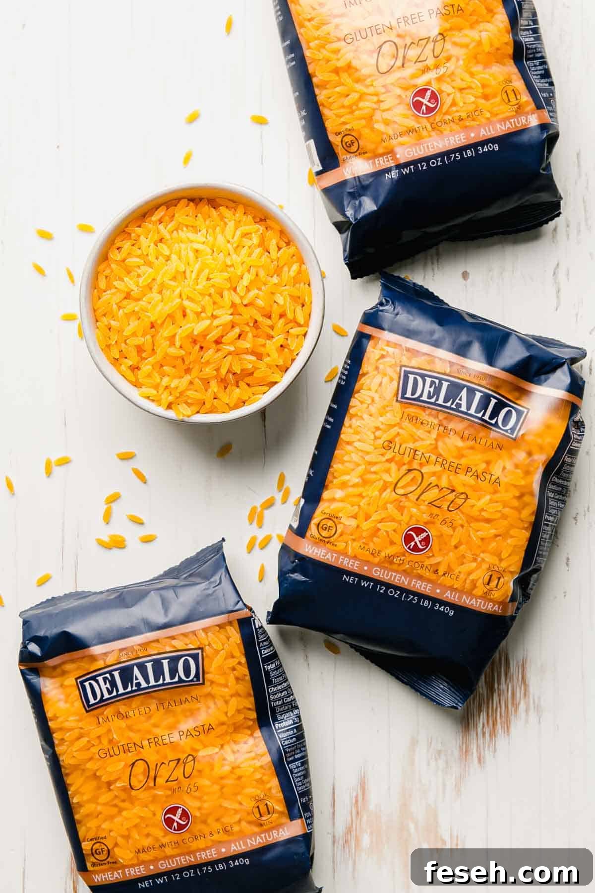 Gluten free orzo in blue bags from Delallo next to a bowl of uncooked gluten-free orzo.