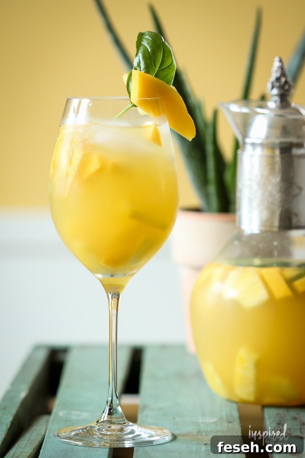 pineapple mango sangria in a glass with mango and basil garnish. 