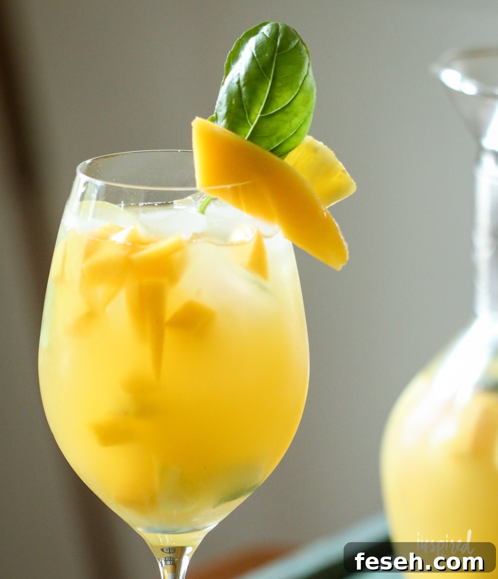pineapple mango sangria in a glass with mango and basil garnish. 