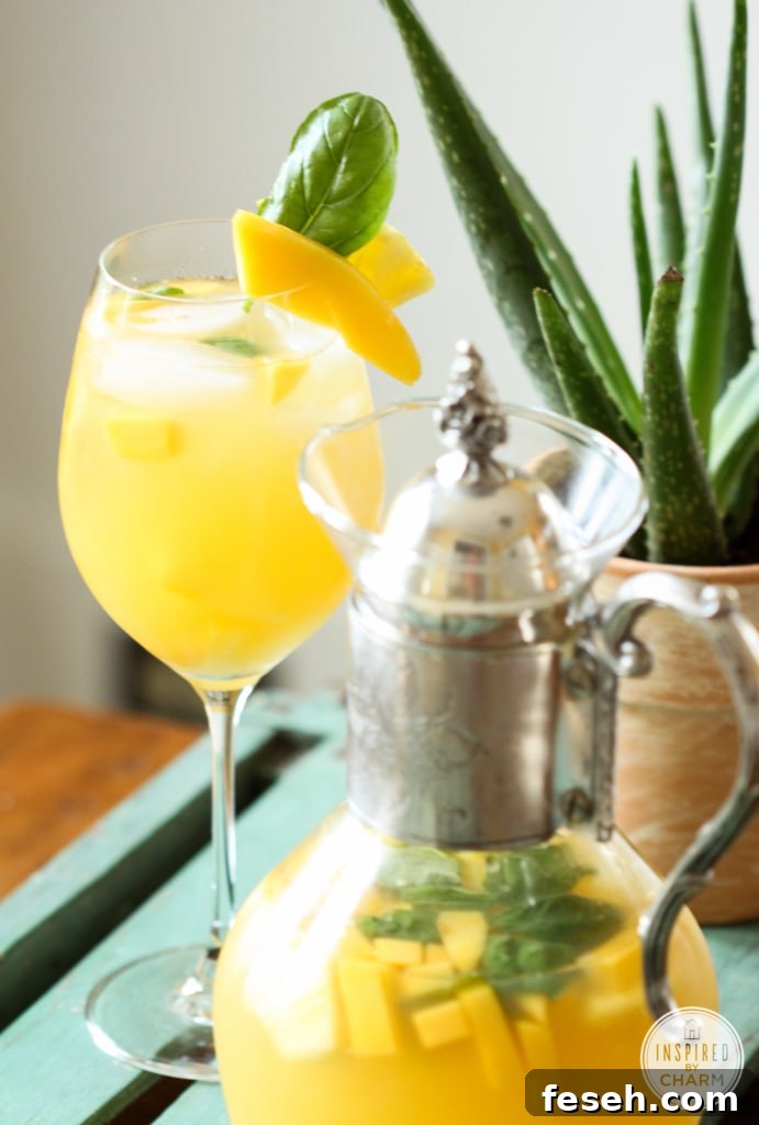 pineapple mango sangria in a glass with mango and basil garnish. 