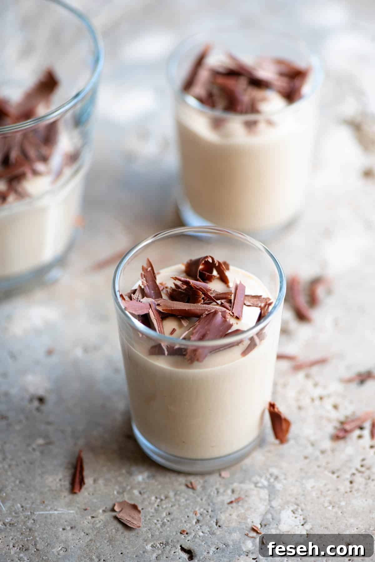 A close up of Ricotta al Caffe (ricotta and coffee) in small glasses topped with dark chocolate. The background is stone.