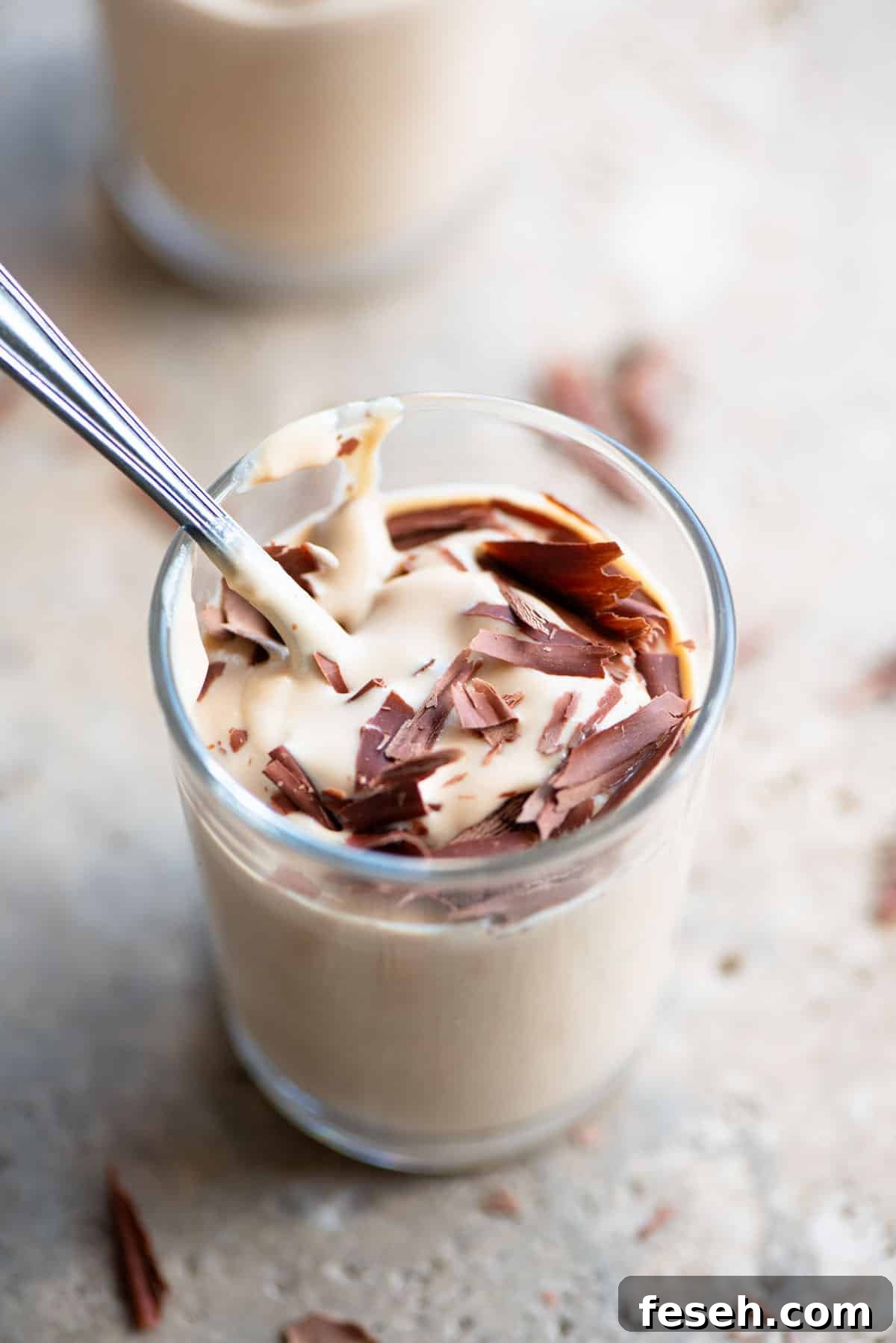 A close up of ricotta and coffee in a small glass with a spoon inside.