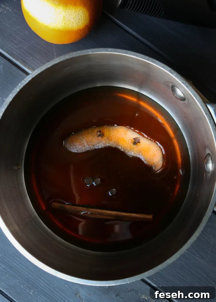 overhead view of orange rind and spices in a sauce pan with maple syrup