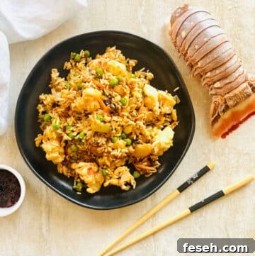 lobster fried rice recipe on plate with chili oil, chopsticks and lobster tail.