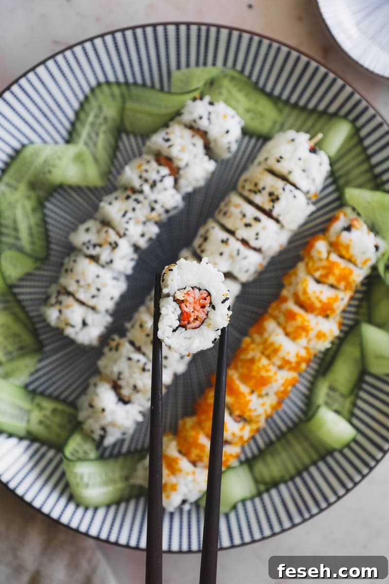 Spicy kani crab roll on a platter with one piece held by chopsticks.