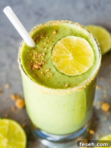 A glass of a key lime pie smoothie topped with a lime slice and crushed graham crackers.