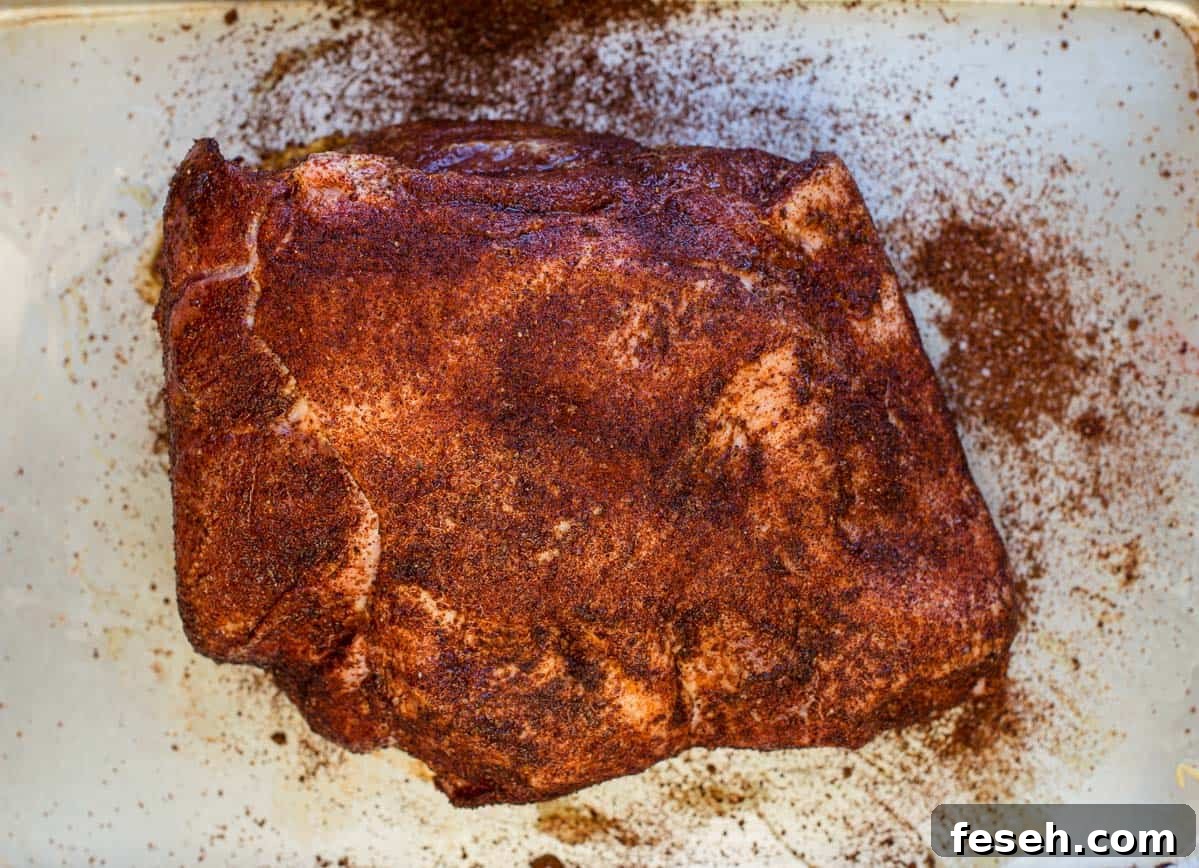 A raw pork butt coated with the best dry rub for pork 
