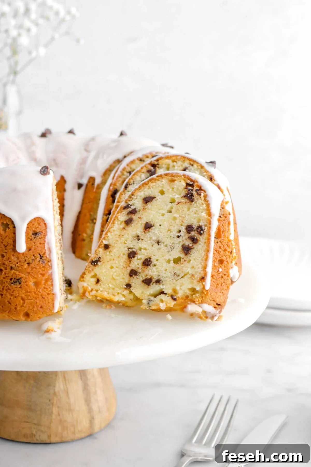 slice of chocolate chip pound cake leaning against more slices and rest of cake on cake stand.