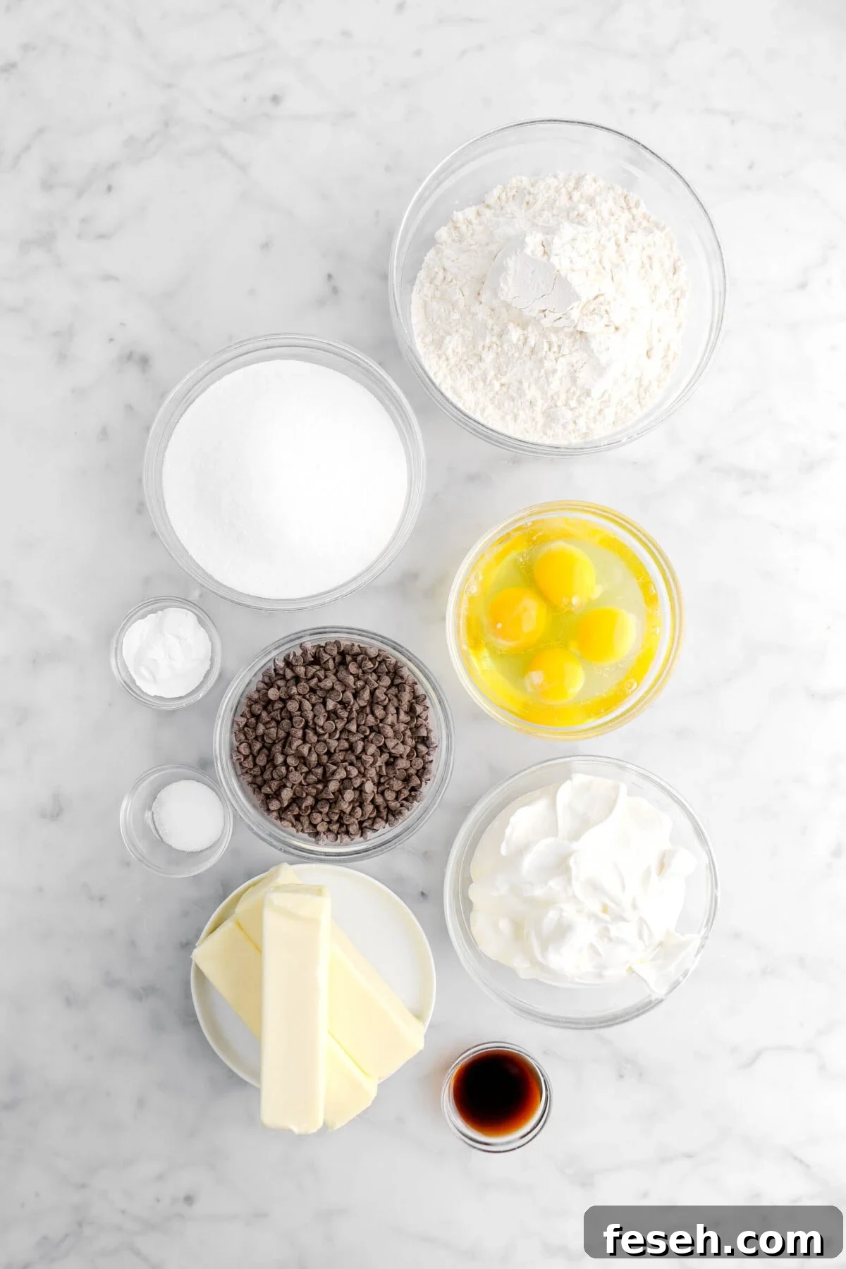 flour, sugar, baking powder, salt, mini chocolate chips, eggs, sour cream, butter, and vanilla on marble surface.