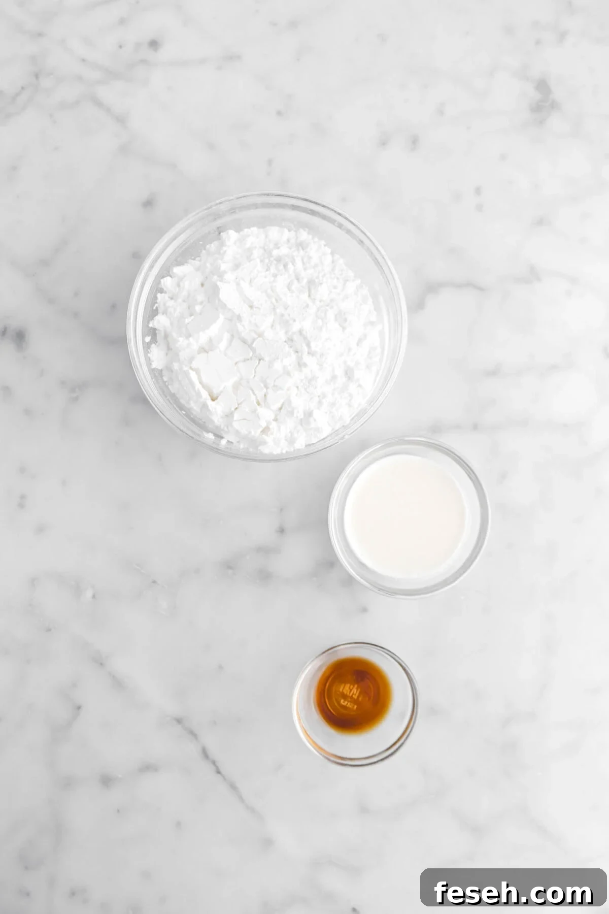 powdered sugar, milk, and vanilla on marble surface.
