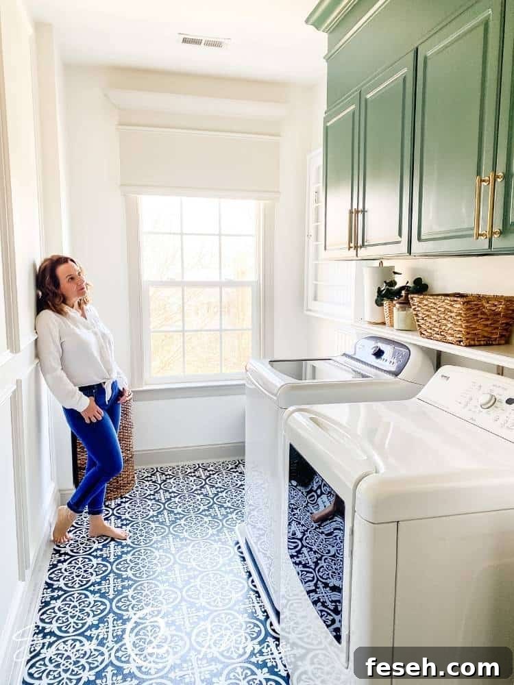 Woman standing in farmhouse-style laundry room looking at painted cabinets