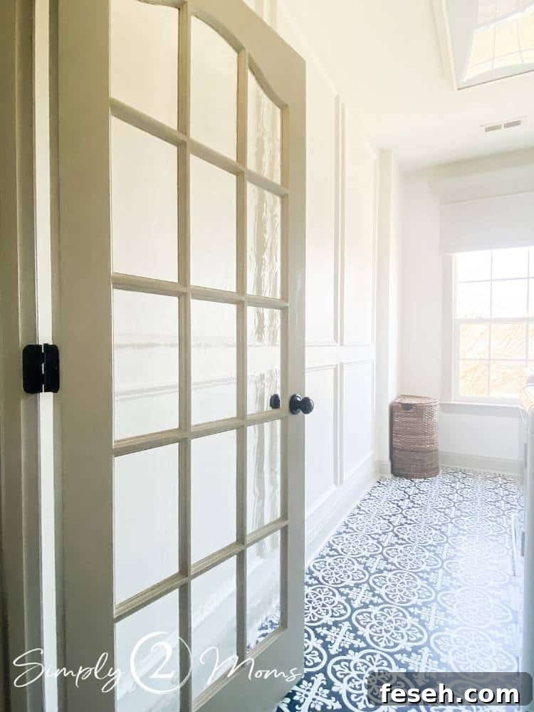 Laundry room with French doors and picture box moulding on the walls and peel and stick tiles with a hand painted ceramic tile look on the floor