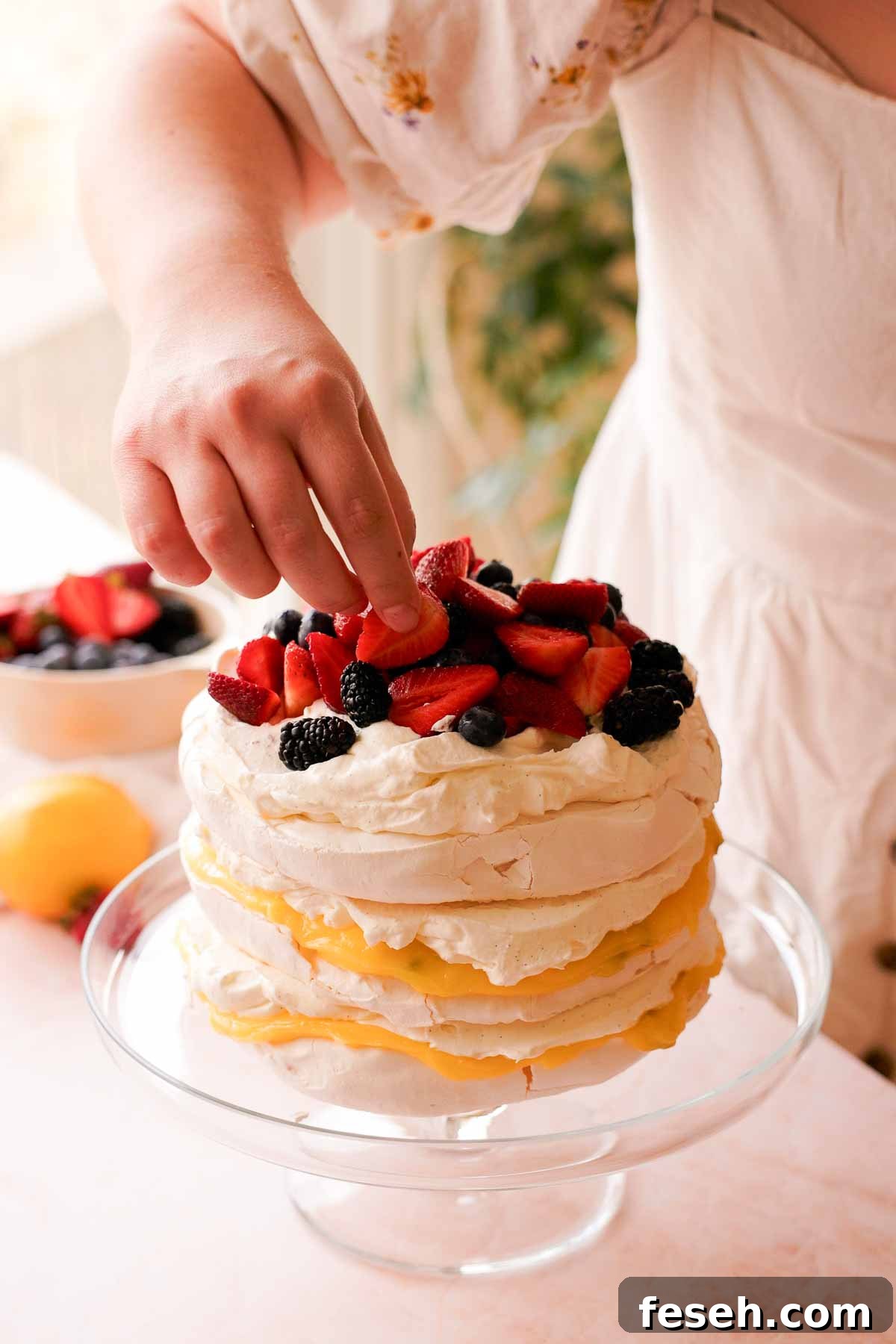 topping stacked pavlova cake with berries