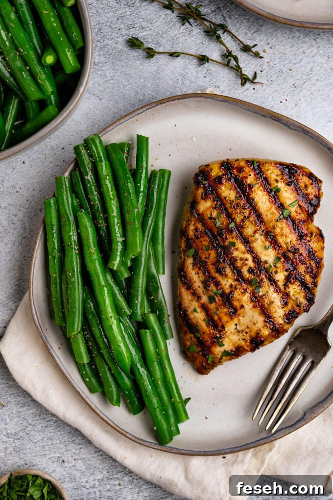 Close up overhead shot of Italian marinated chicken on a gray plate with green beans on the side.