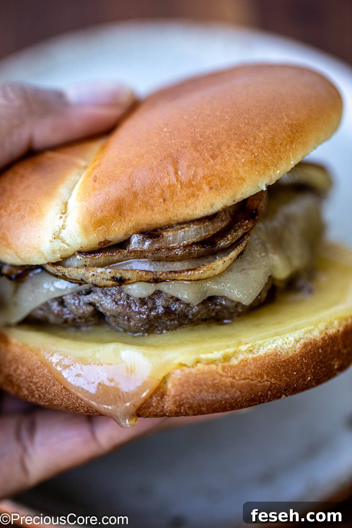 Hand holding a grilled burger.