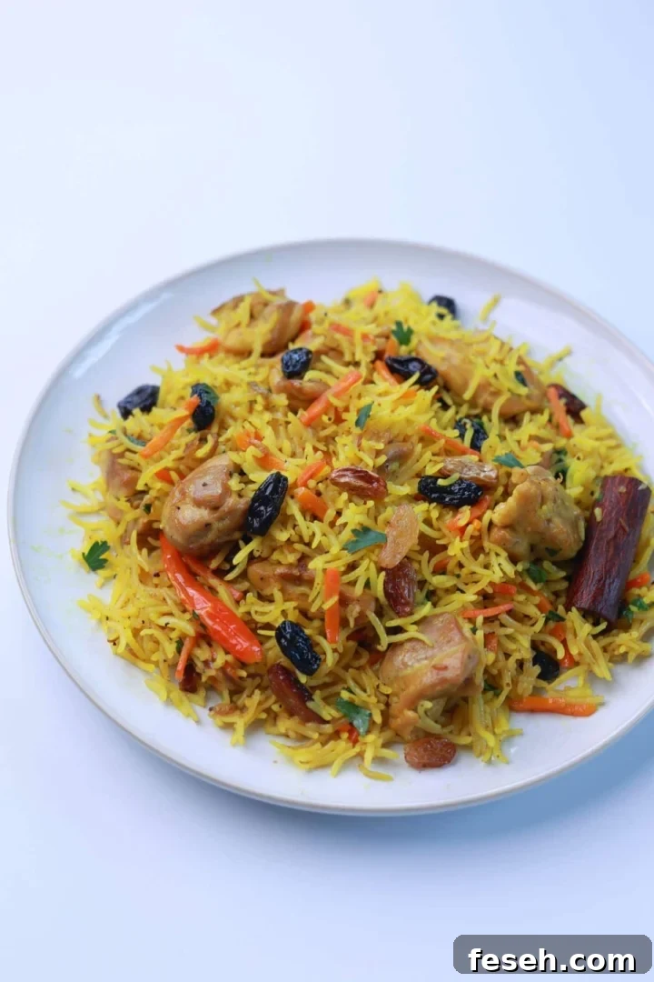 A delicious serving of easy one-pot chicken pilaf on a white plate, garnished with parsley, showcasing the golden rice, tender chicken, and raisins.
