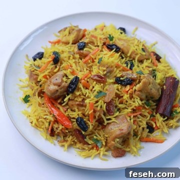 Close-up of easy one-pot chicken pilaf served on a white plate, showing the golden, fragrant rice, tender chicken, and raisins.