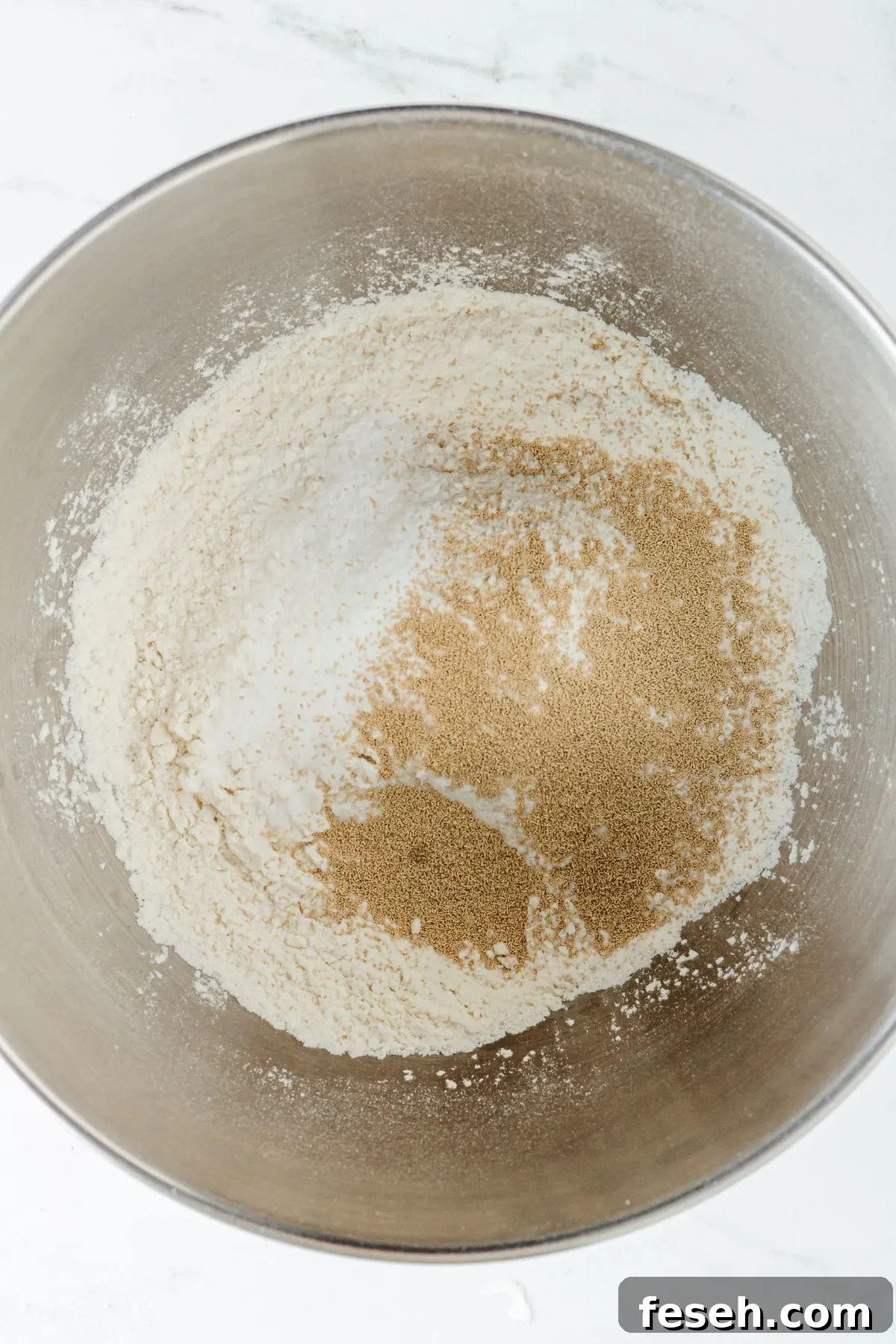 A stand mixing bowl with gluten-free flour blend, baking powder, and instant yeast. 