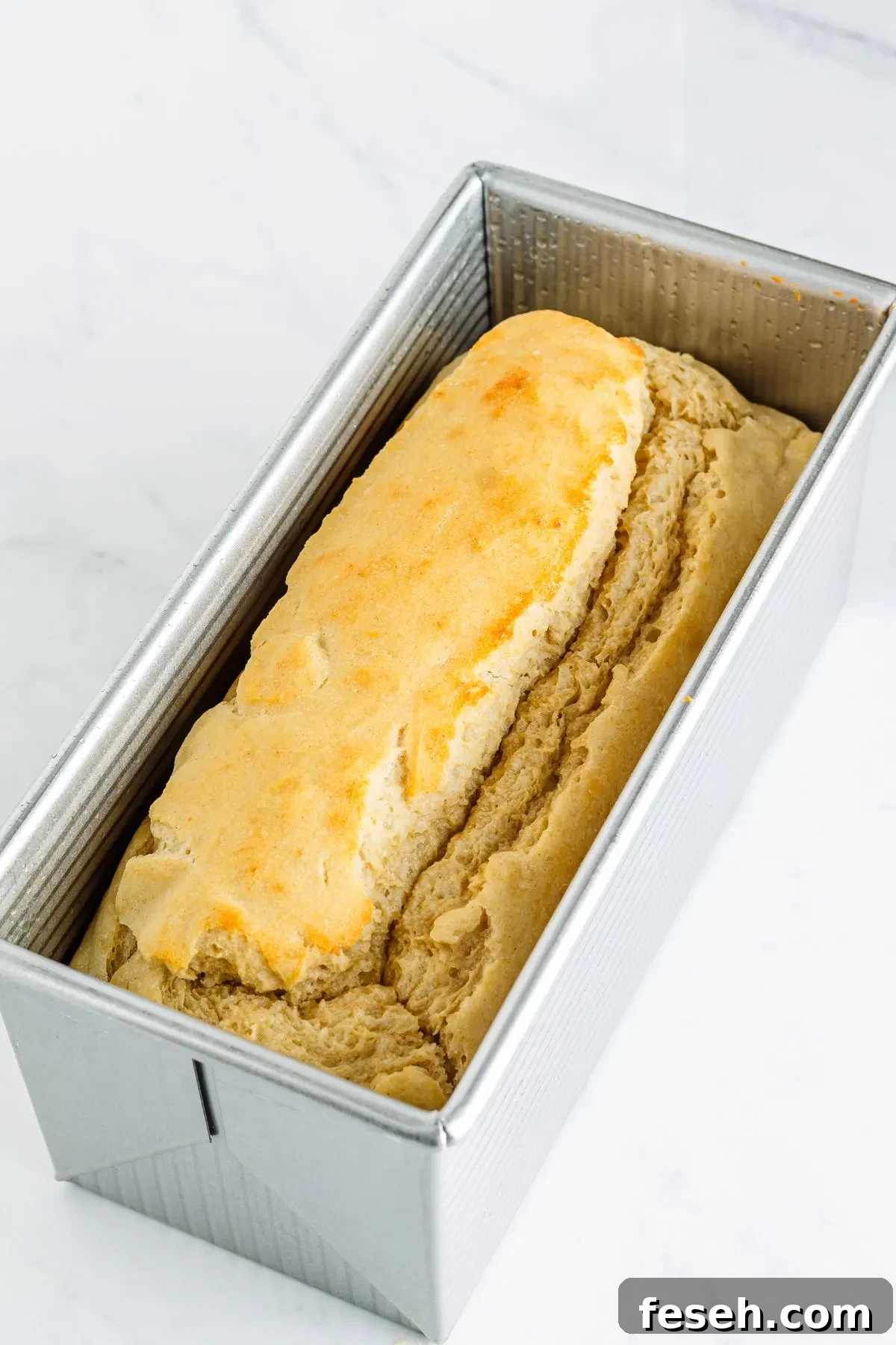 A fresh baked loaf of gluten-free dairy-free soy-free white bread in a Pullman loaf pan.