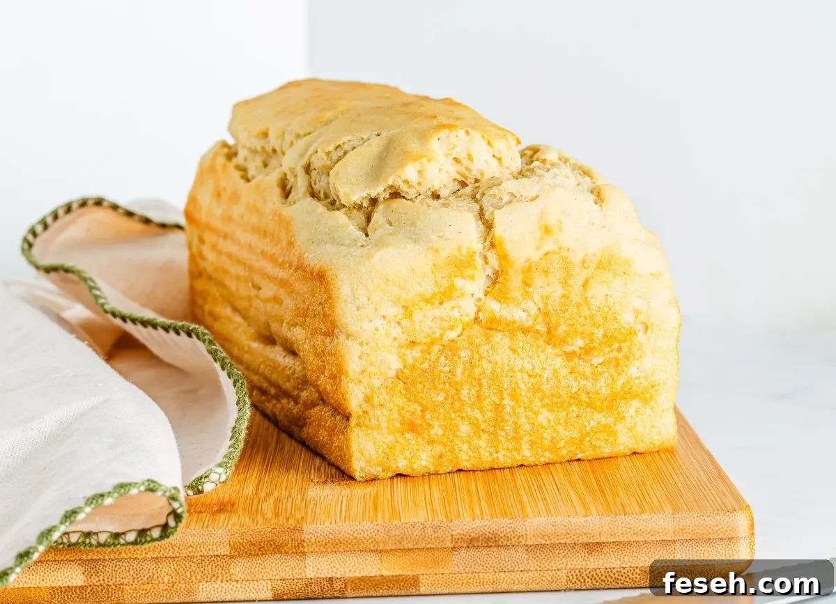 A beautiful homemade loaf of gluten free white bread on a cutting board.