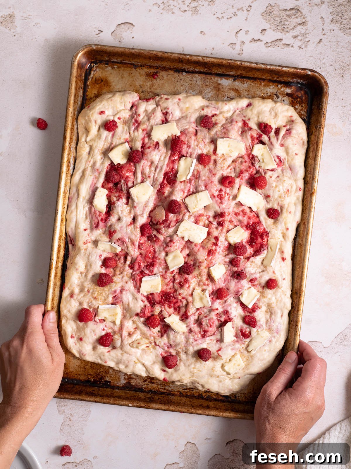 Homemade focaccia dough topped with raspberries and brie cheese