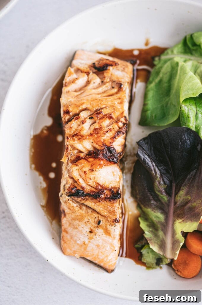 overhead closeup: salmon filet with teriyaki glaze on white plate with garden salad
