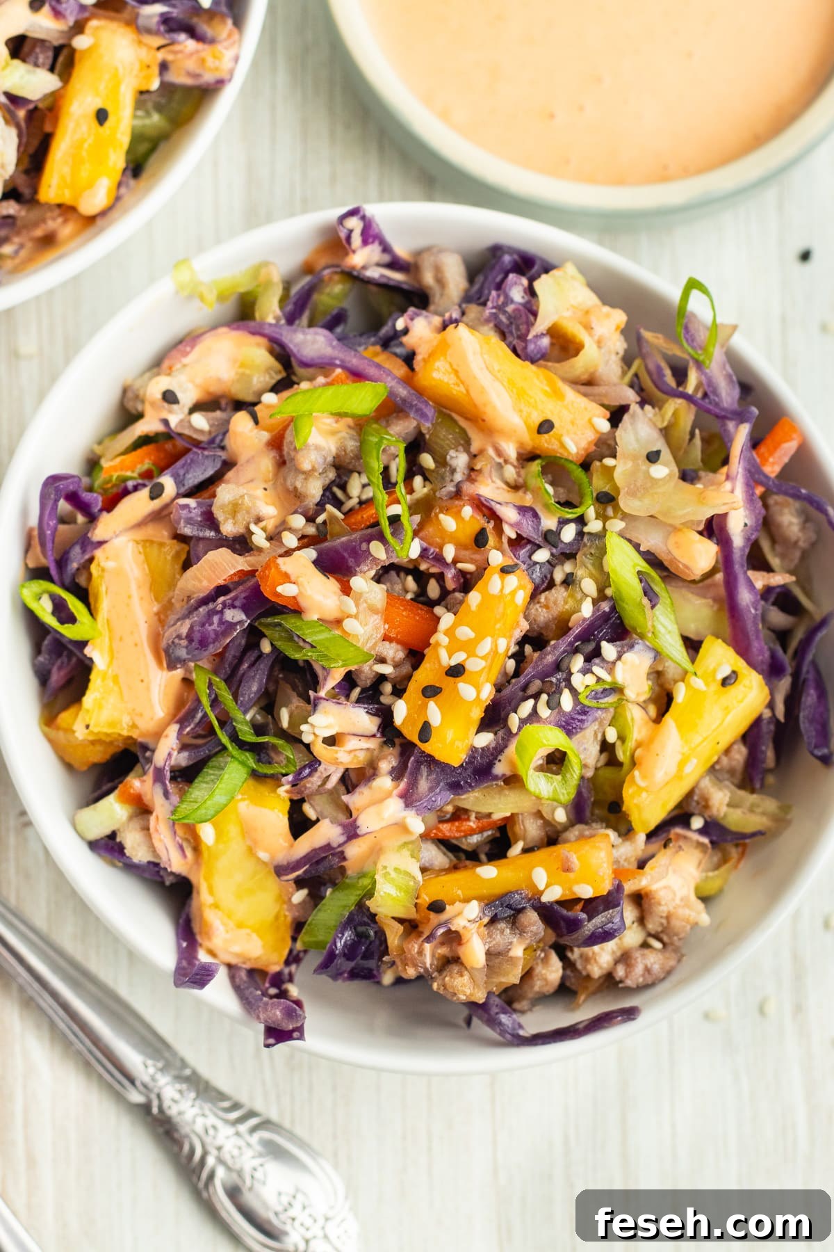 Picture of an individual bowl filled with egg roll in a bowl with pineapple.