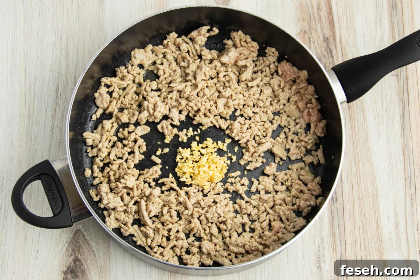 Picture of a skillet with ground chicken, minced garlic and ginger.