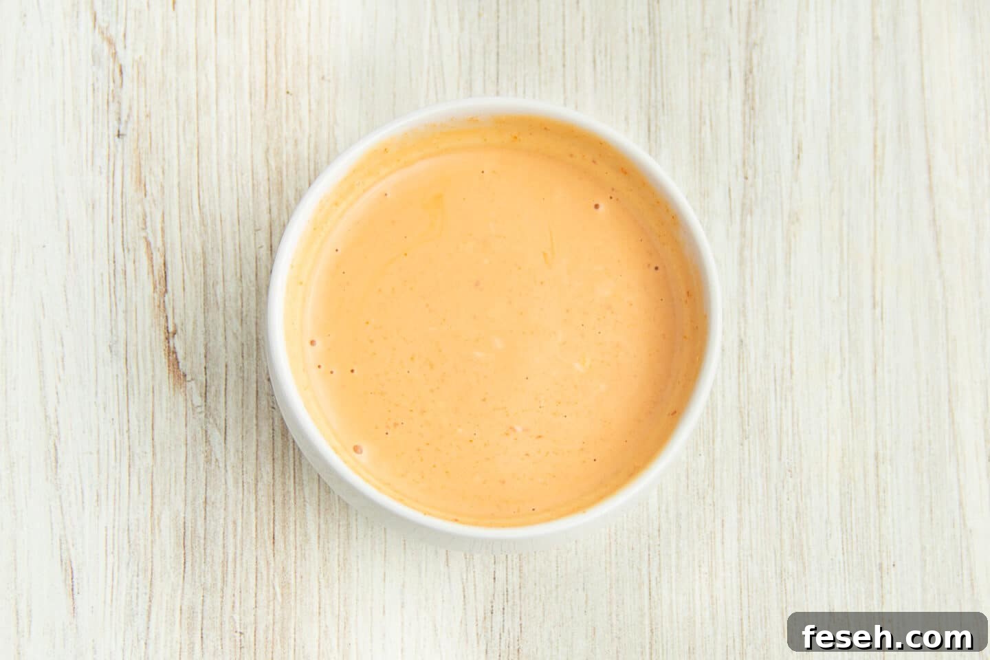 Picture of a small white bowl with sriracha mayonnaise sauce.