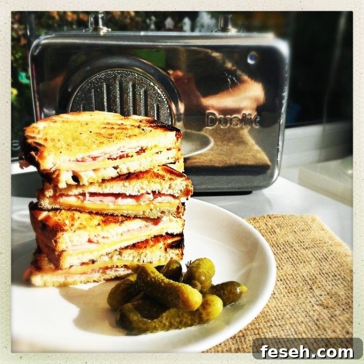 toasted ham and cheese sandwiches piled up on a plate with a side of cornichons Dualit stainless steel radio in the background
