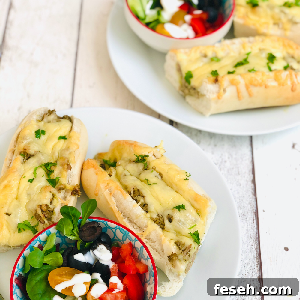 homemade tuna melt baguettes served on white dinner plates with a small bowl of side salad