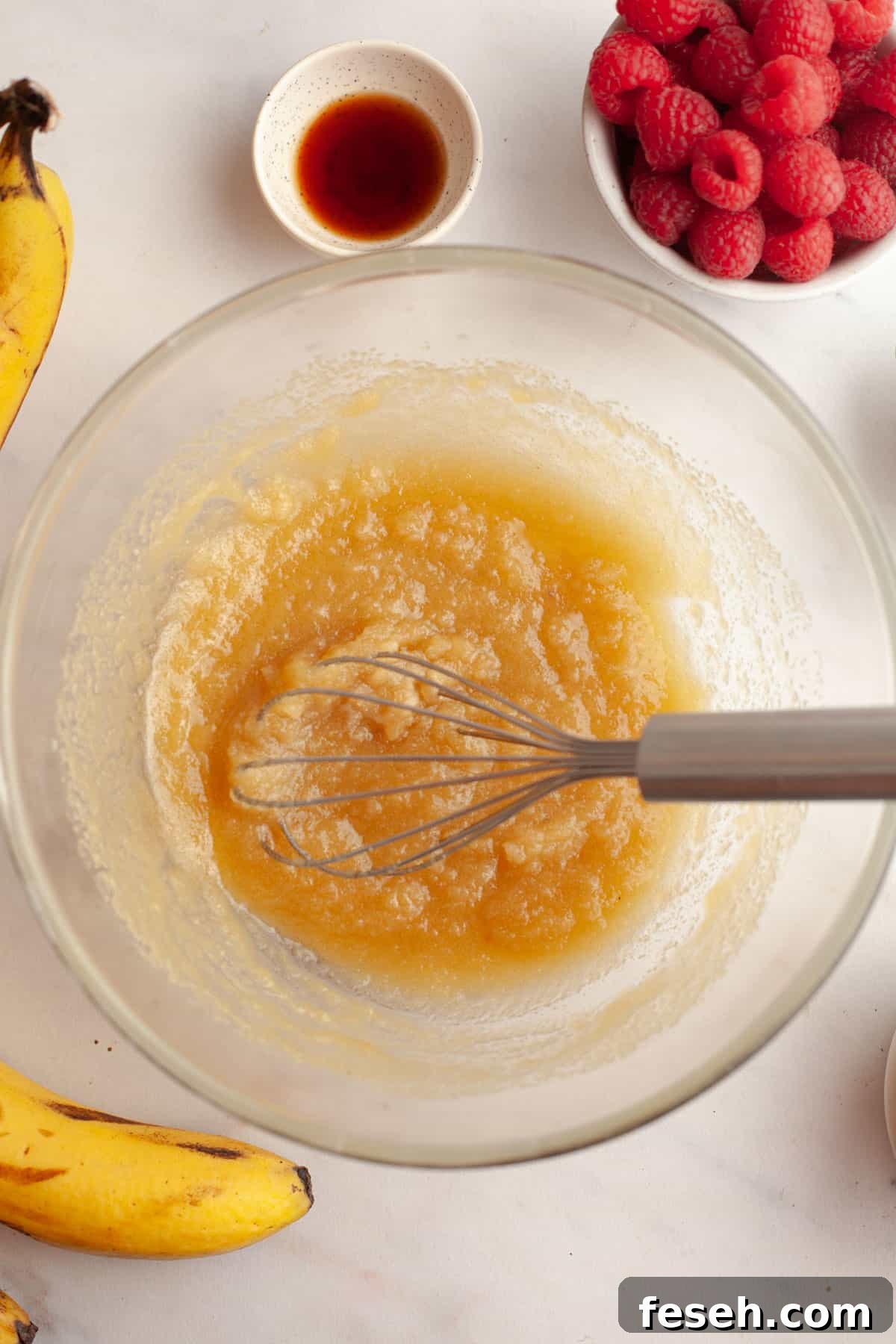 A bowl with a whisk and melted butter and sugar in it.